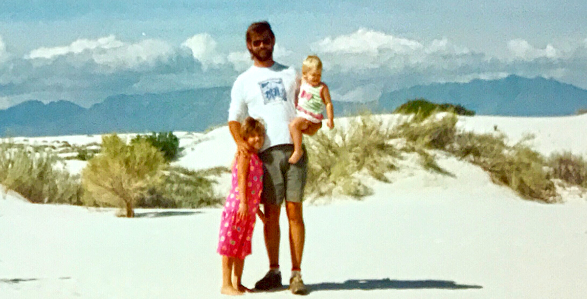 Mariah Amstutz as a toddler, being held by her father, Ronnie on a beach. Next to them is Mariah's sister, Stacy