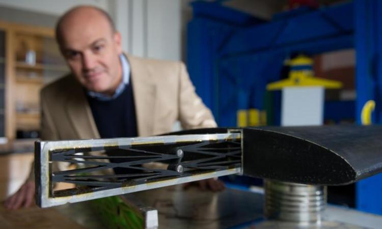 <p><em>Massimo Ruzzene, a professor in the School of Aerospace Engineering, designs metamaterials, which are synthetic composite structures with properties not found in materials derived from nature. Here he demonstrates a structure that could help reduce structural fatigue caused by continual flexing in aircraft wings. (Click image for high-resolution version. Credit: Rob Felt)</em></p>