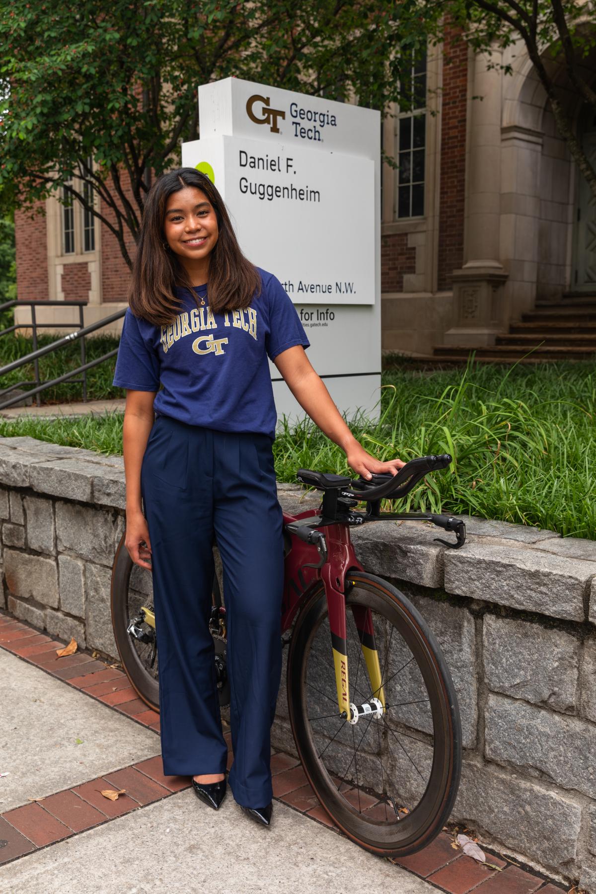 Elise Regalado standing in front of the Guggenheim building with her cycling bike used in her triathlon. 